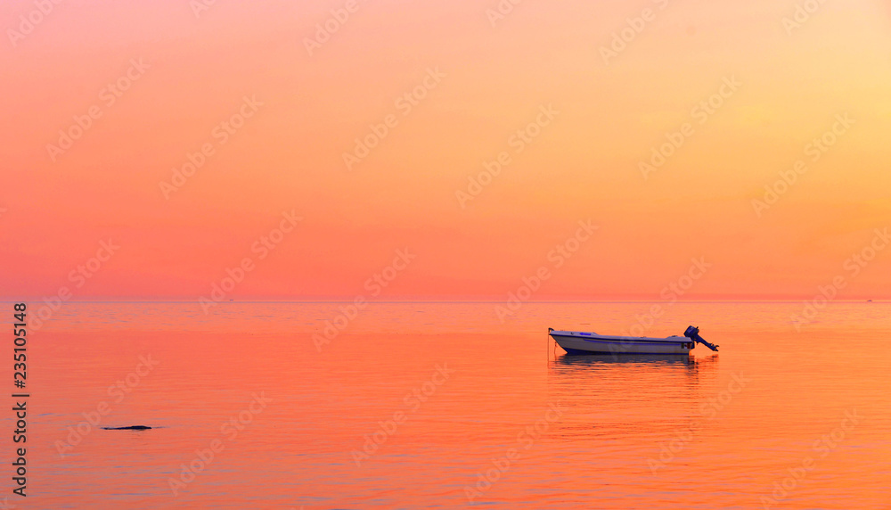 a peaceful sea with warm sunset colors and a solitary boat in a beach near Agrigento in Sicily Italy