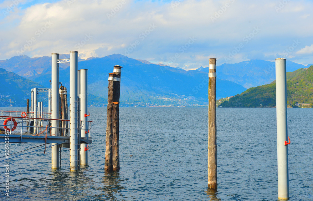 empty dock in Pallanza on Lake Maggiore with blue water and cloudy sky and rays of light in Verbania, Italy