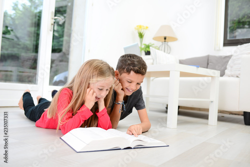 two young happy kids brother and sister together having fun at home reading encyclopedia book photo