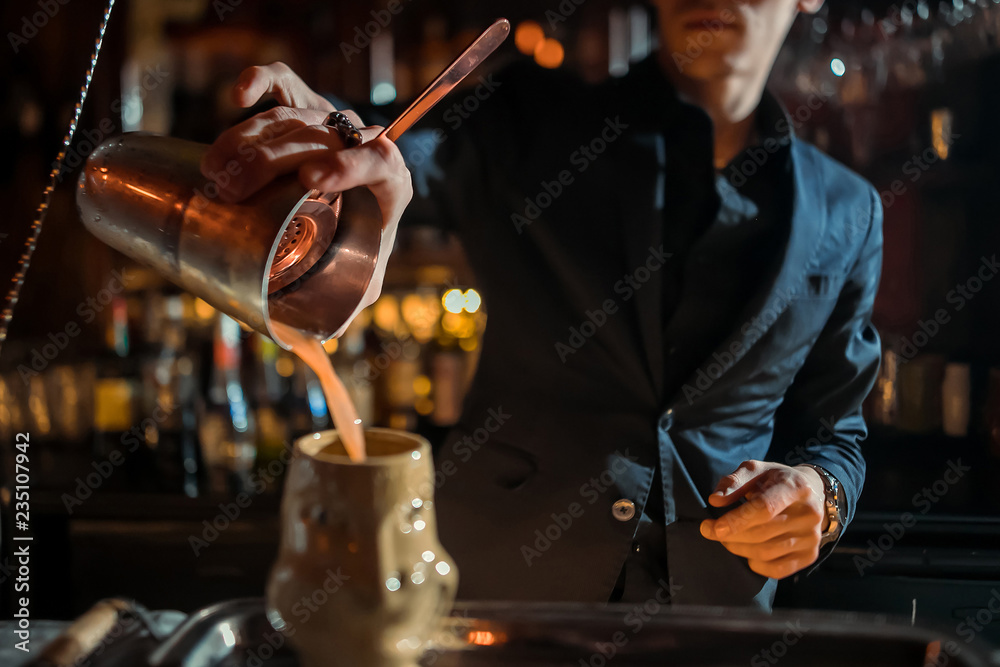 The bartender strains a cocktail in a glass at a nightclub, beach, pub, restaurant