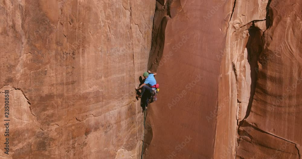 Aerial view of extreme rock climber topping out on multi pitch climb 
