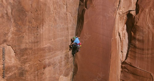 Aerial view of extreme rock climber topping out on multi pitch climb  photo