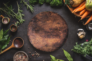 Food cooking and healthy eating background with round wooden cutting board and fresh seasoning, spoon and vegetables, top view, frame. Copy space for your text and design