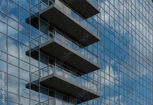 Reflection of the sky and clouds in the Windows of a multi-storey glass building. Several open balconies
