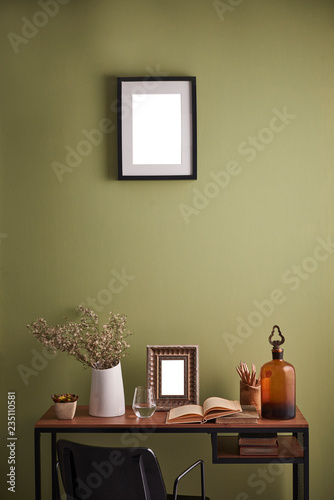 Modern wooden desk frame on the green wall with black chair.