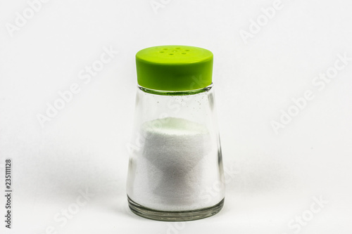 A mini bottle container of salt with plastic green lid. Isolated in white. 