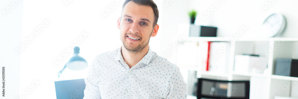 A young man stands leaning on a table in the office. A young man stands leaning on a table in the office.