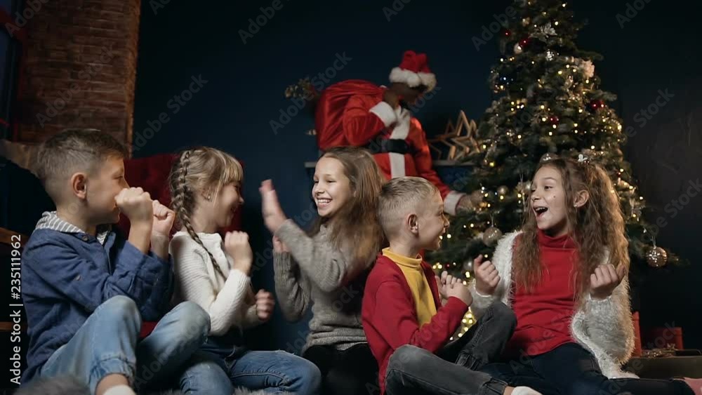 Happy cute kids playing, laughing and giving five on the background with african man in the santa claus costume. Happy cute kids playing, laughing and giving five on the background with african man in the santa claus costume.