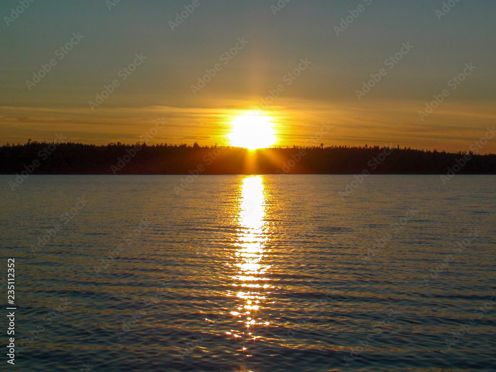 Naklejka premium Orange sunset and glowing path on the lake in Karelia