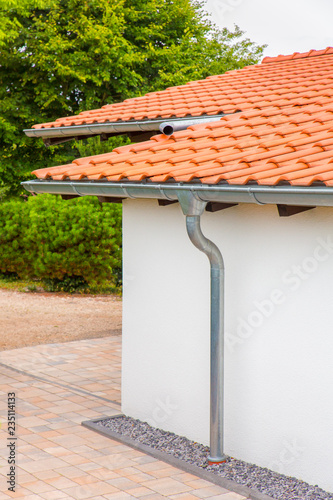 Roof of house with gutters and rain pipe