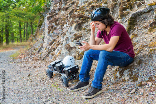 Young dutch man sits with mountainboard and cellphone