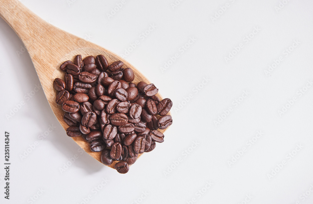 Many coffee beans in the wood spoon and white background. Many coffee beans in the wood spoon and white background.