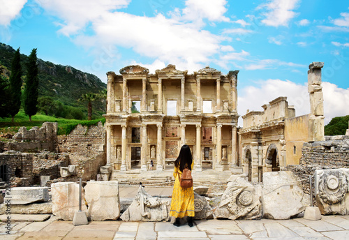 Canvas Print A young Asian tourist woman wearing yellow dress enjoying the view at Library of Celsus at Ephesus which is an ancient Roman building in Ephesus, Anatolia and now part of Selçuk, Turkey