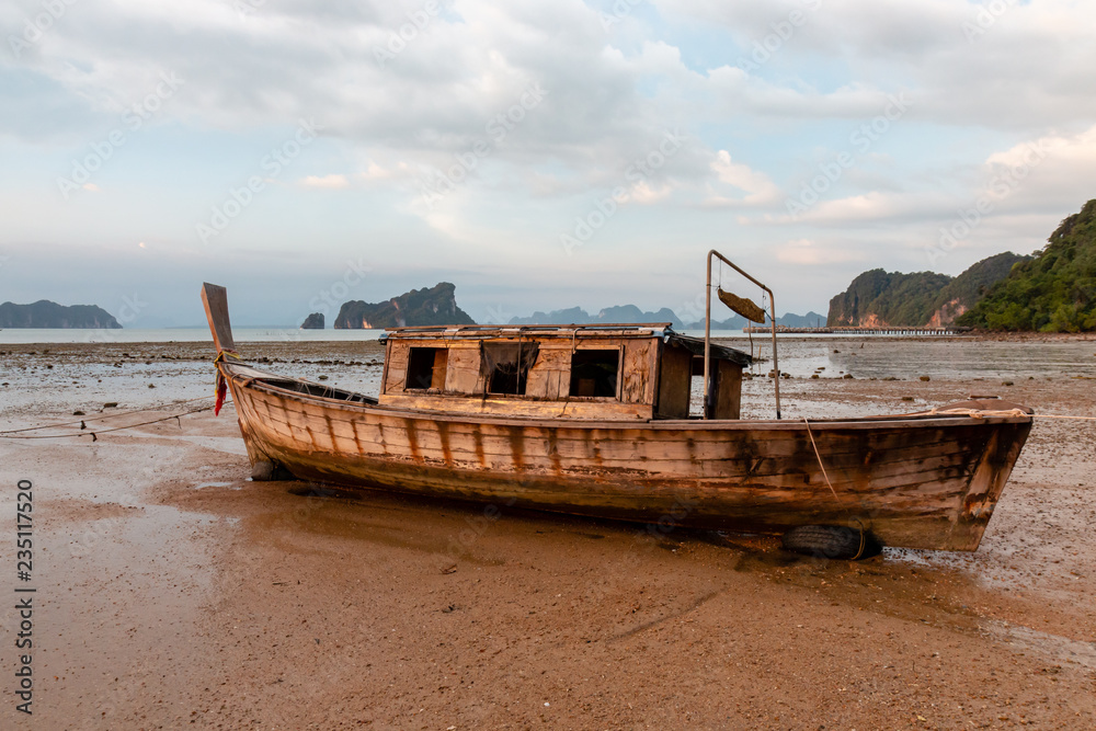 An old wooden boat at low tide at sunset on a tropical island (Koh Yao Noi, Thailand)