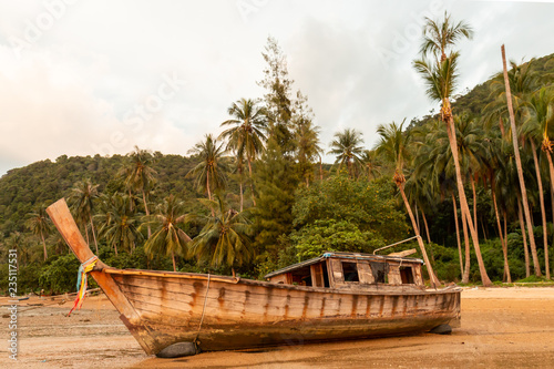 An old wooden boat on a tropical beaching during a beautiful, colorful sunset © whitcomberd