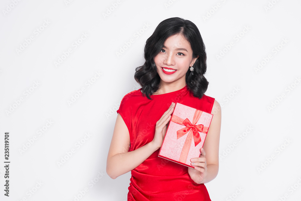 Beautiful Asian girl holding a present in her hands and smiling against the white background Beautiful Asian girl holding a present in her hands and smiling against the white background