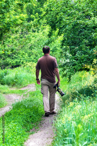 Hiking outdoor photographer walks in green forest, back view