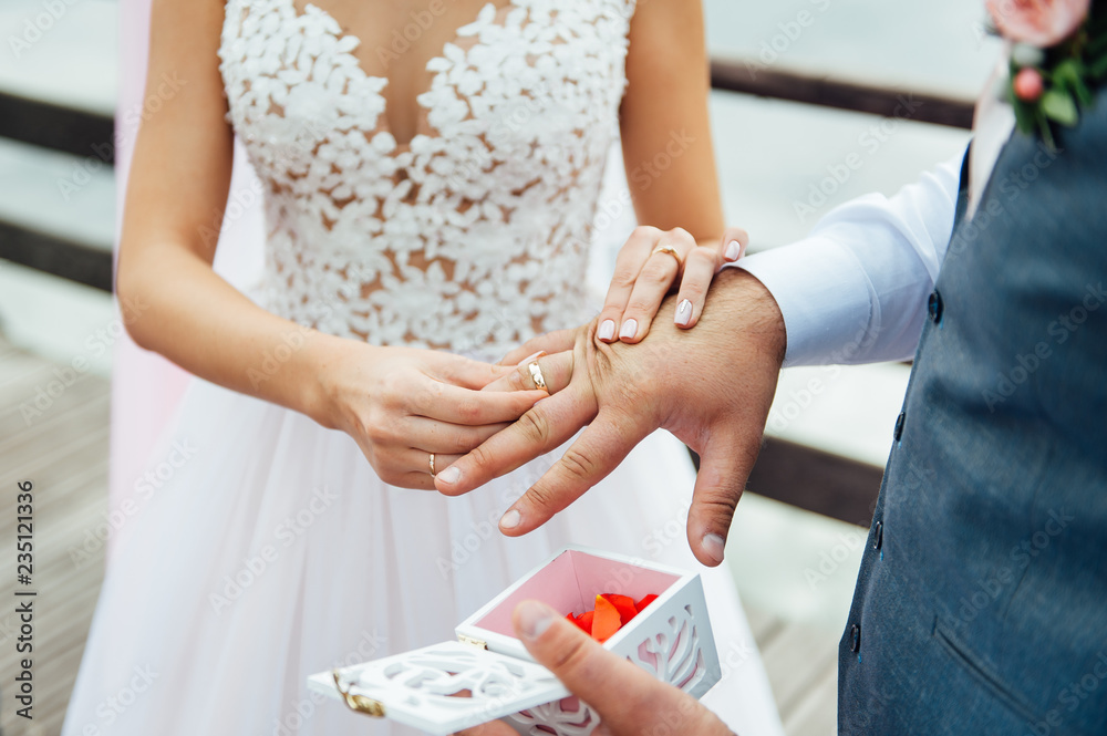 The groom wears the bride a wedding ring at the ceremony The groom wears the bride a wedding ring at the ceremony