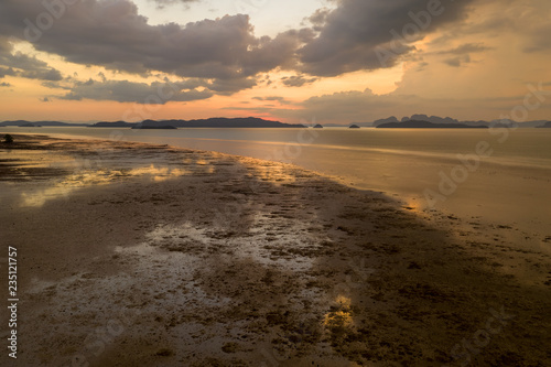 Aerial view of a colorful tropical sunset over a beach and calm ocean