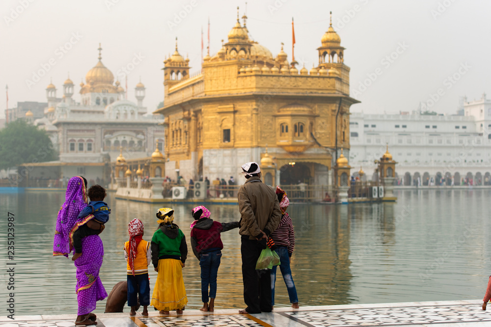 An indian family is admiring the majestic Golden Temple of Amritsar in the state of Punjab, India.