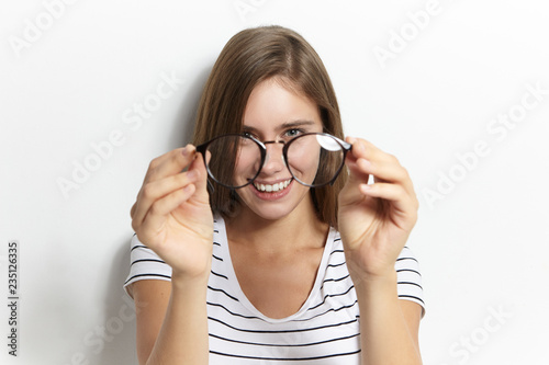 People  lifestyle  health  eyewear  optics and vision concept. Portrait of happy cheerful young woman holding stylish glasses close to camera  doesn t need them anymore because of contact lenses