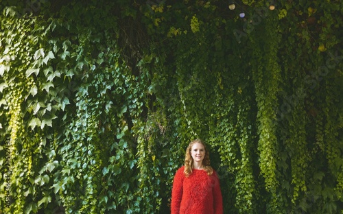 Woman standing against plant creeper in outdoor cafe