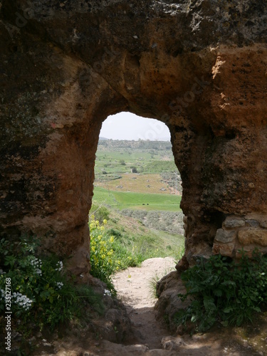 View of a rural landscape through an old red stone gate in the mountains of Ronda