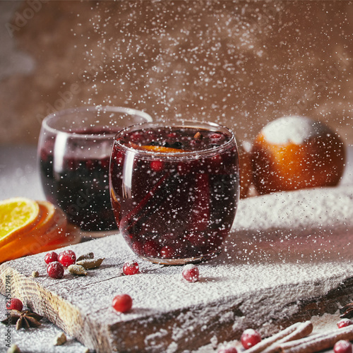 homemade mulled wine with cranberries and falling powdered sugar in kitchen