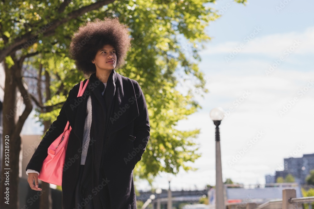 Young woman with afro hair walking on street Stock 写真 | Adobe Stock