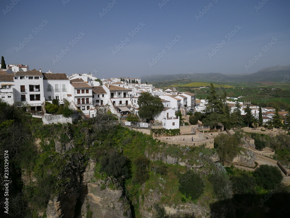 White houses of a city in the mountains behind a canyon in Ronda, Spain