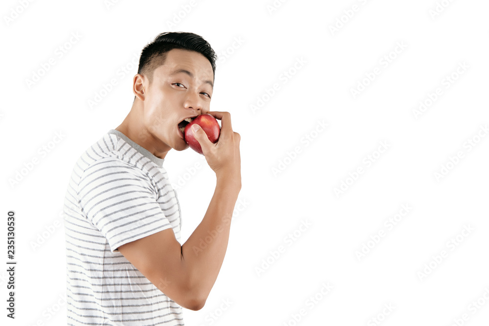 Waist-up portrait of good-looking Asian man eating organic red apple and looking at camera against white background, copy space Waist-up portrait of good-looking Asian man eating organic red apple and looking at camera against white background, copy space