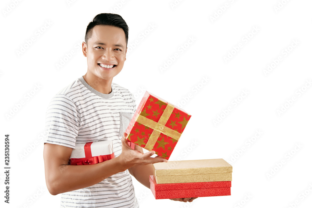 Portrait of young handsome Asian man holding wrapped Christmas presents and smiling at camera joyfully against white background Portrait of young handsome Asian man holding wrapped Christmas presents and smiling at camera joyfully against white background