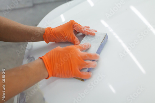 men's hands in orange gloves take the form of the hood for the subsequent eipoking of the car. man working in a car garage