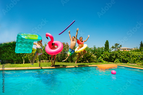 Joyful teens with swim tools jumping into the pool