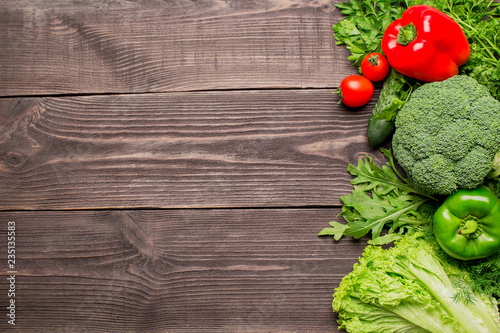 Frame of green and red fresh vegetables on wooden background, top view