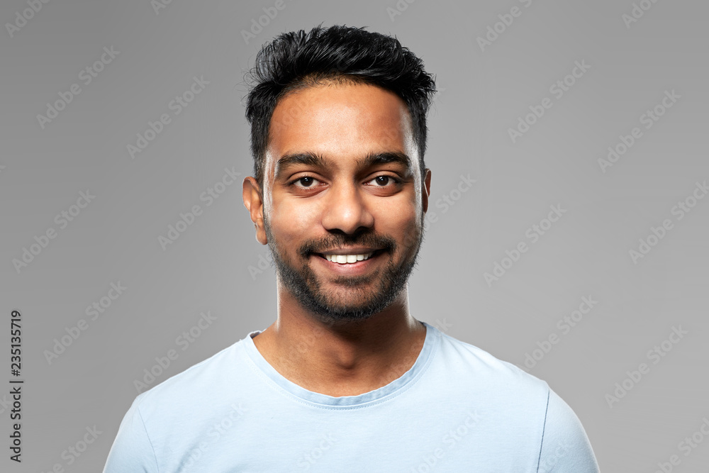 Fototapeta premium people concept - smiling young indian man over grey background