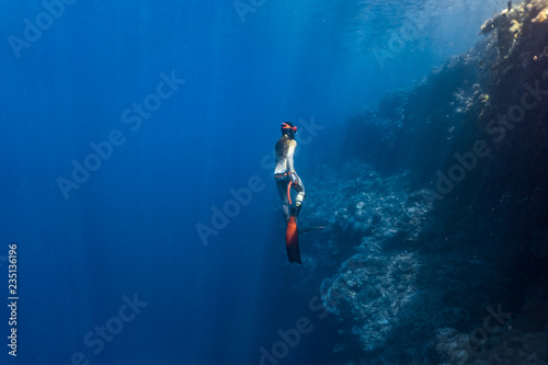 Sexy free diver wearing bikini ascends to the surface from a deep breath hold dive