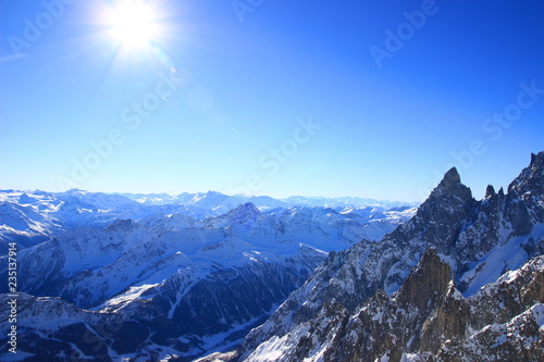 Sun on blue sky above Alps covered with snow