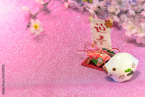 Glitter background for japanese New Year's Cards with cute animal figurine of boar or pig and rice paper with handwriting ideograms Geishun which means Welcome Spring. photo