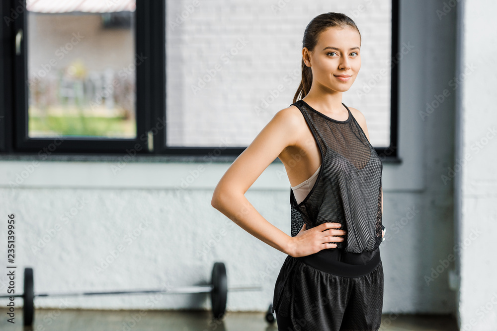 attractive fit sportswoman in black with hands on hips looking at camera at gym attractive fit sportswoman in black with hands on hips looking at camera at gym