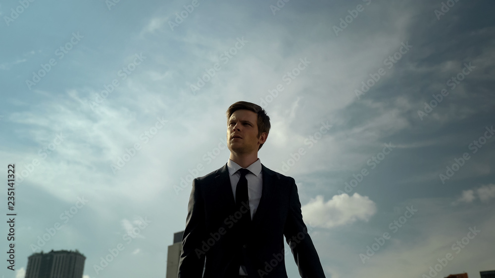 Young self-confident young businessman walking outdoors, success concept, city Young self-confident young businessman walking outdoors, success concept, city
