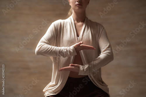 Calm young lady meditating and putting hands at the level of the stomach while practicing chi gong photo