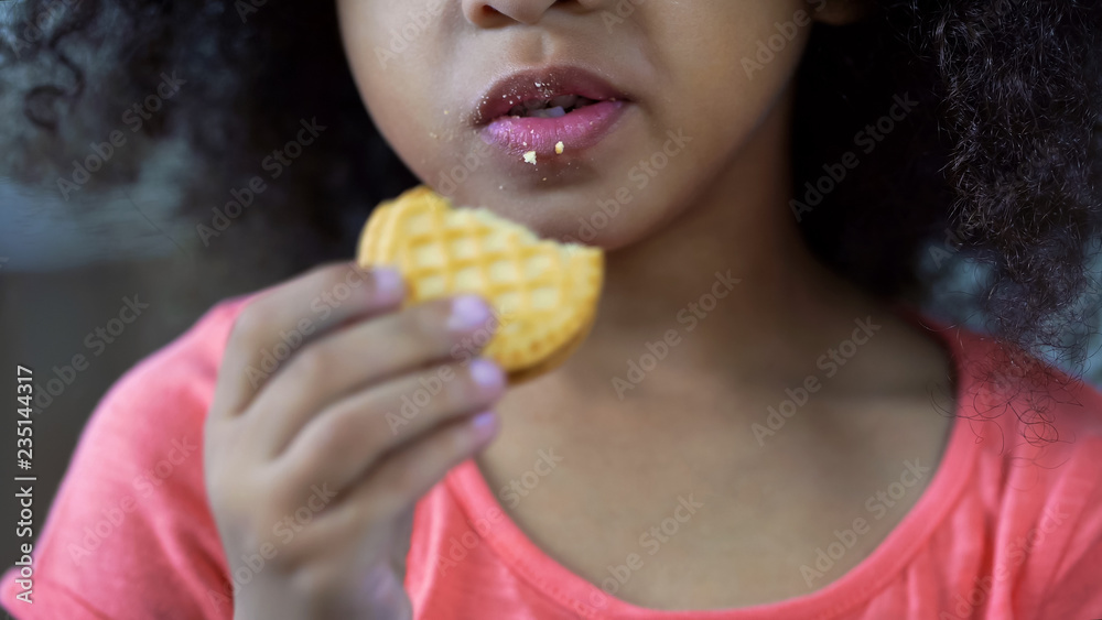 Little nice girl eating sweet cookie, lips cowered with crumbs, unhealthy food Little nice girl eating sweet cookie, lips cowered with crumbs, unhealthy food
