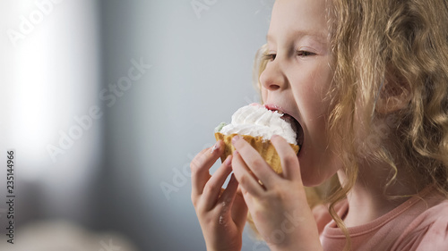 Pretty little Caucasian girl eating cake and enjoying perfect taste of dessert