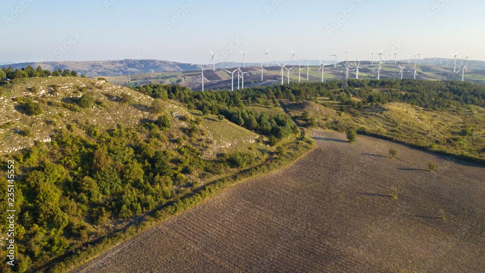 Aerial view at morning of wind turbines for renewable sources of electricity without pollution. These sustainable eco-friendly structures are built in the mountains of Irpinia, in Italy.