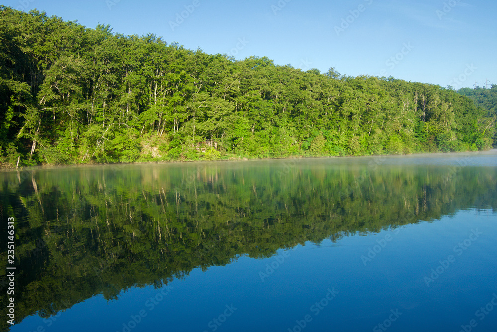 Nature landscape of the Arno River with woods and reflection on the water Nature landscape of the Arno River with woods and reflection on the water