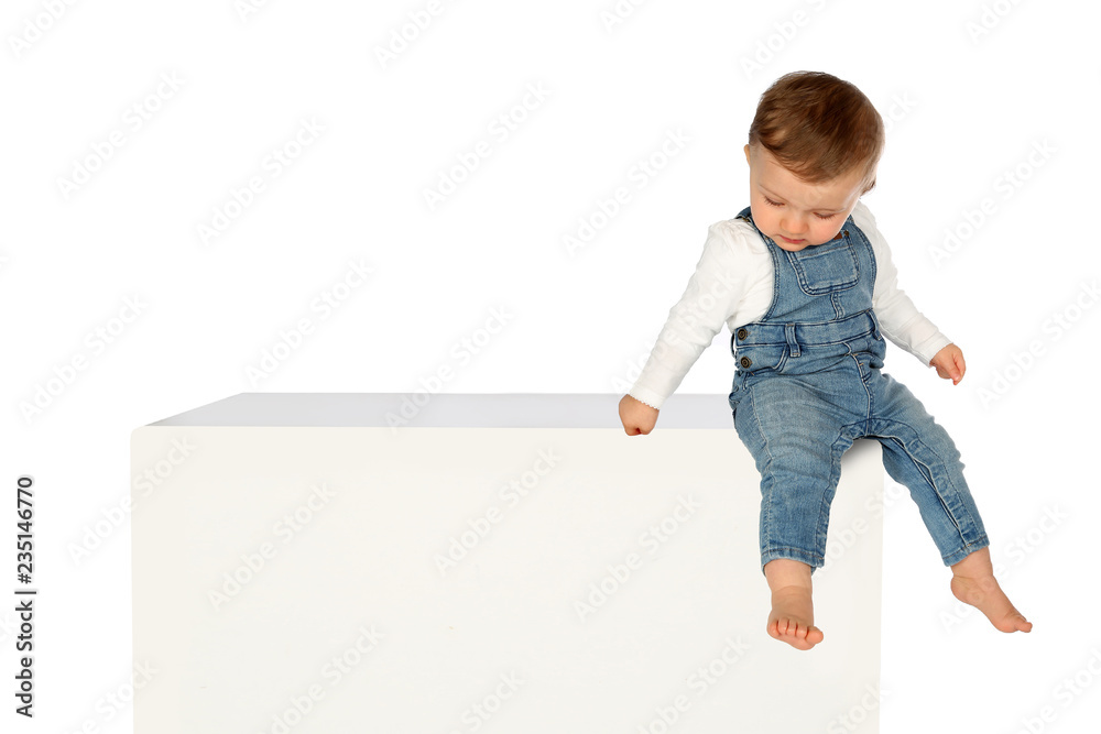 Kleines Kind sitzt auf einem weissen Kasten Kleines Kind sitzt auf einem weissen Kasten