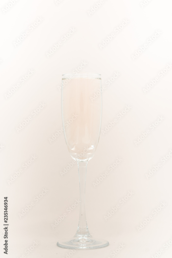 A glass of champagne with bubbles. Christmas balls and a golden lights on light abstract background. A glass of champagne with bubbles. Christmas balls and a golden lights on light abstract background.