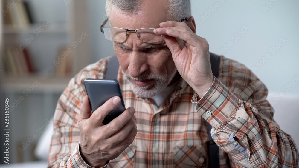 Bewildered old man looking at cellphone, new technology complicated for elderly Bewildered old man looking at cellphone, new technology complicated for elderly