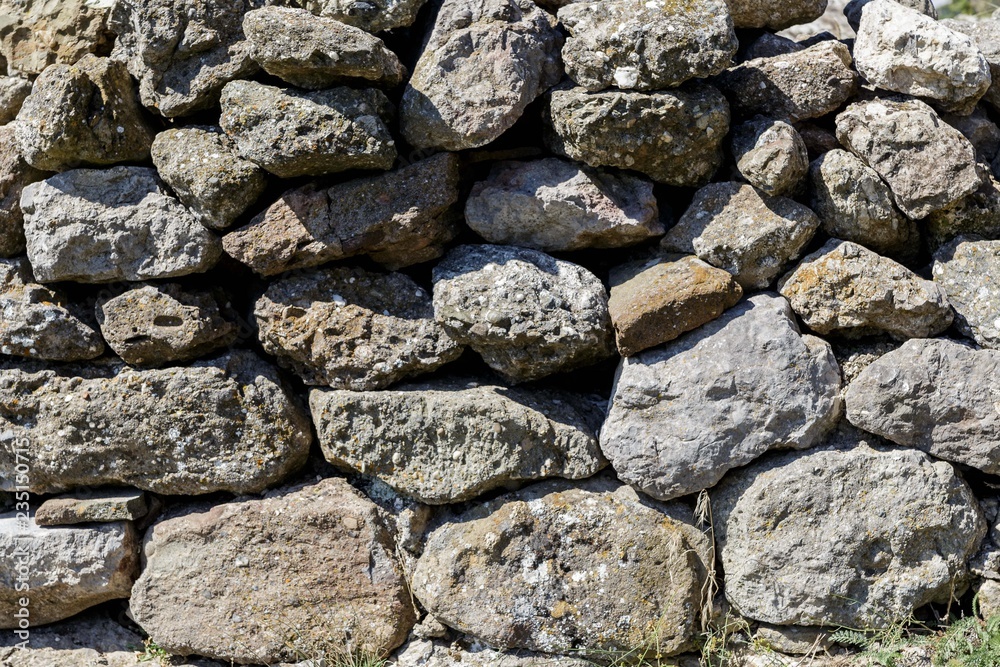 The wall of the ancient fortress is made of stones. Texture.